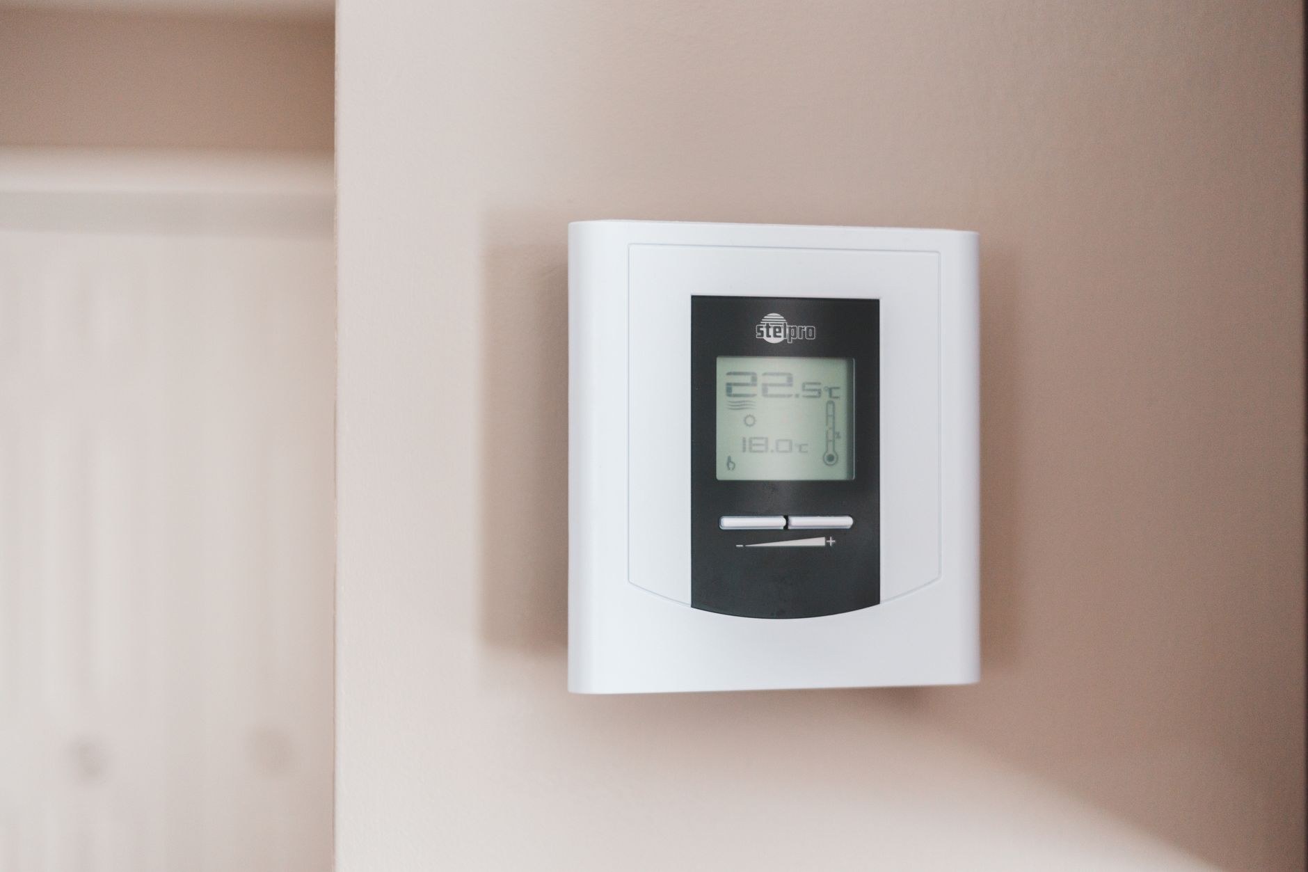 A wall-mounted heat pump control being checked